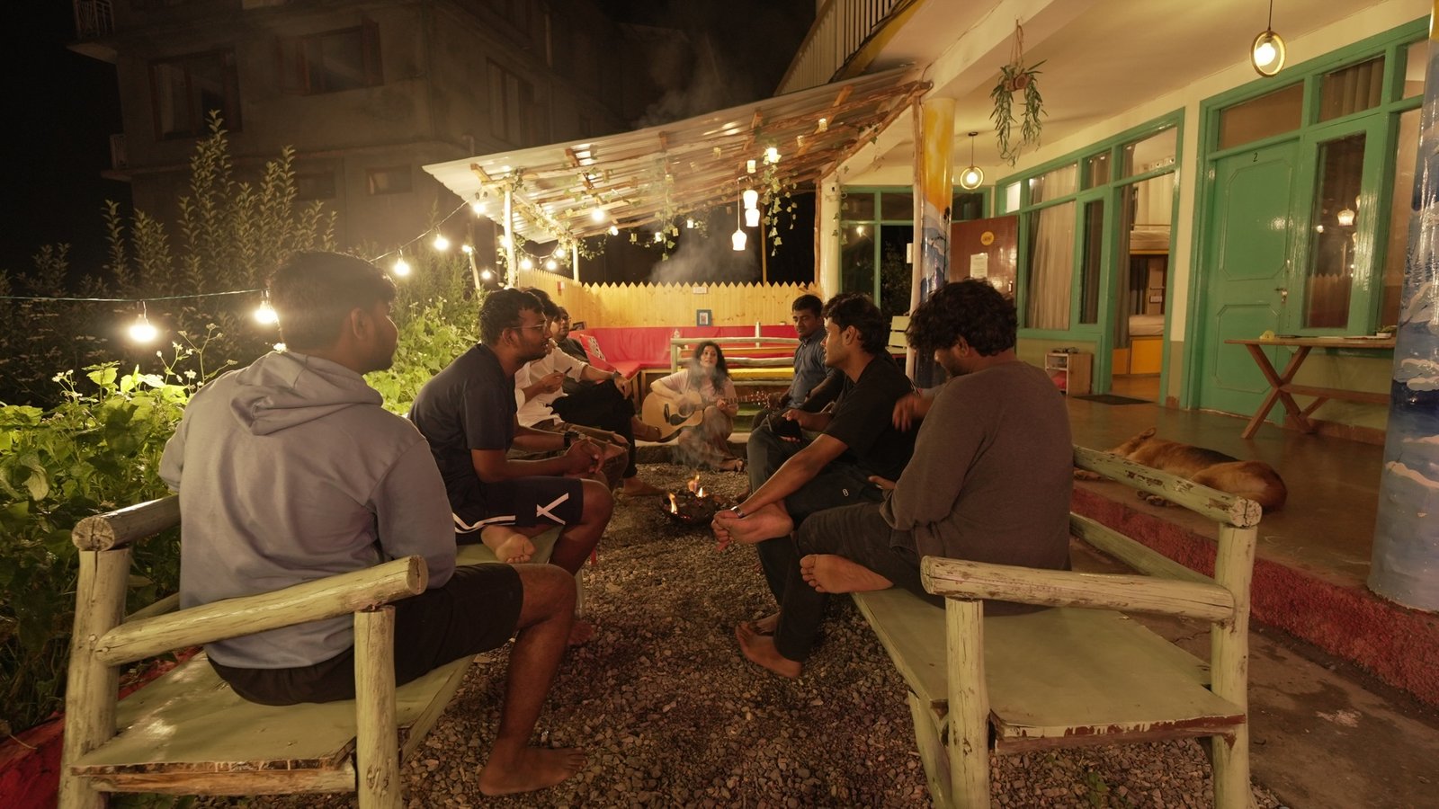 Safar guests gathered around a terrace bonfire with a guitar