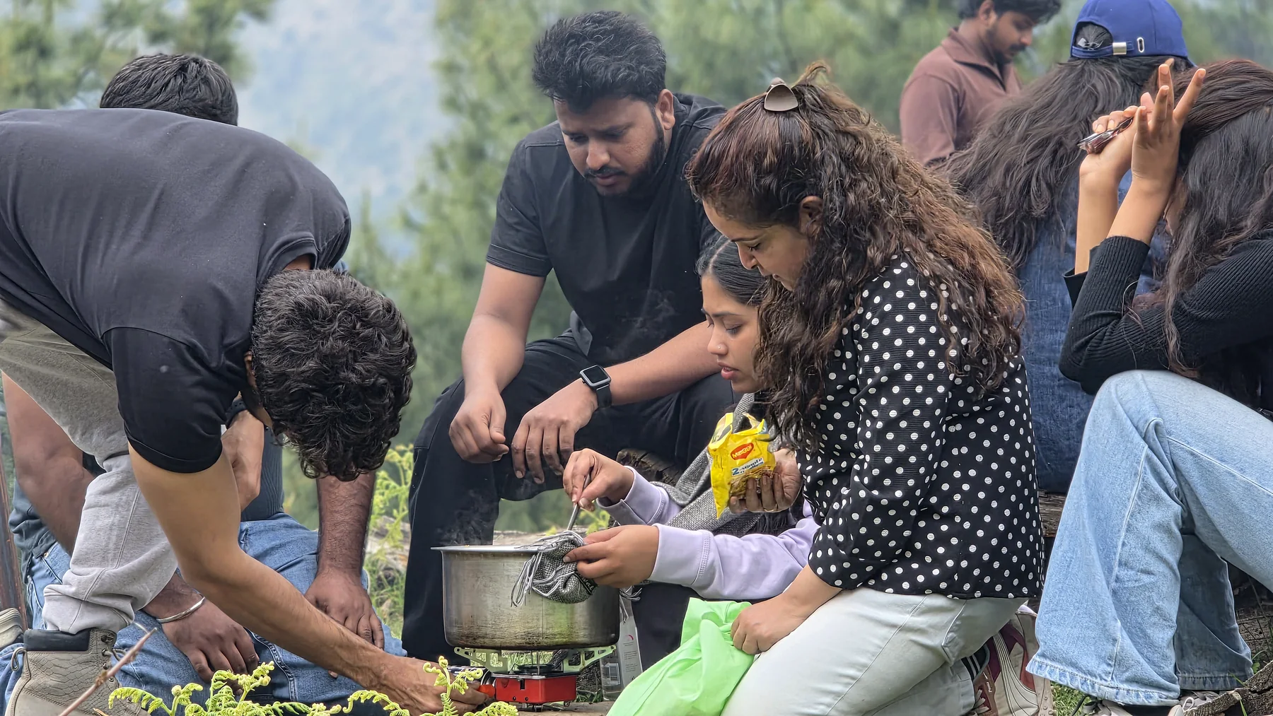 Guests preparing a shared outdoor meal on a portable stove