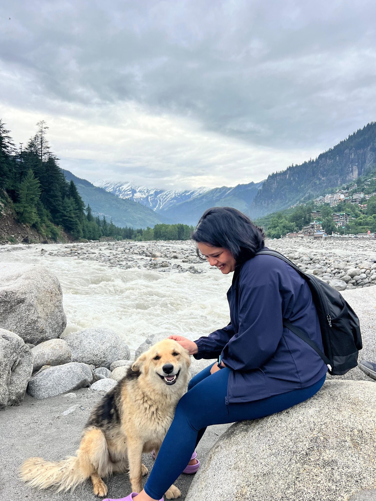 Traveller and mountain dog beside a fast-flowing river